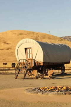 Covered wagon, fire pit, and chairs in a field