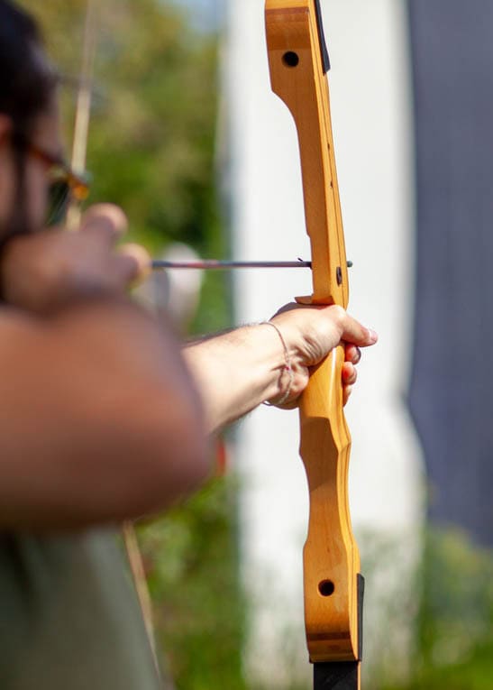 Person aiming and shooting a wooden bow and arrow