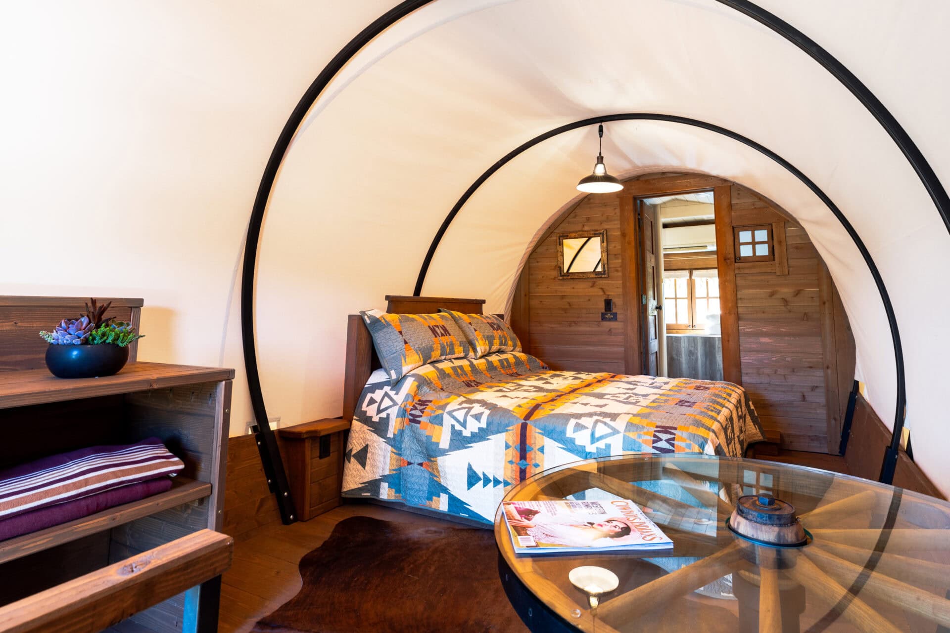 Cozy wooden cabin bedroom with colorful quilt and table.