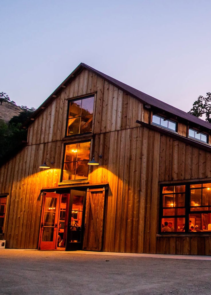 Rustic barn with lit windows at dusk