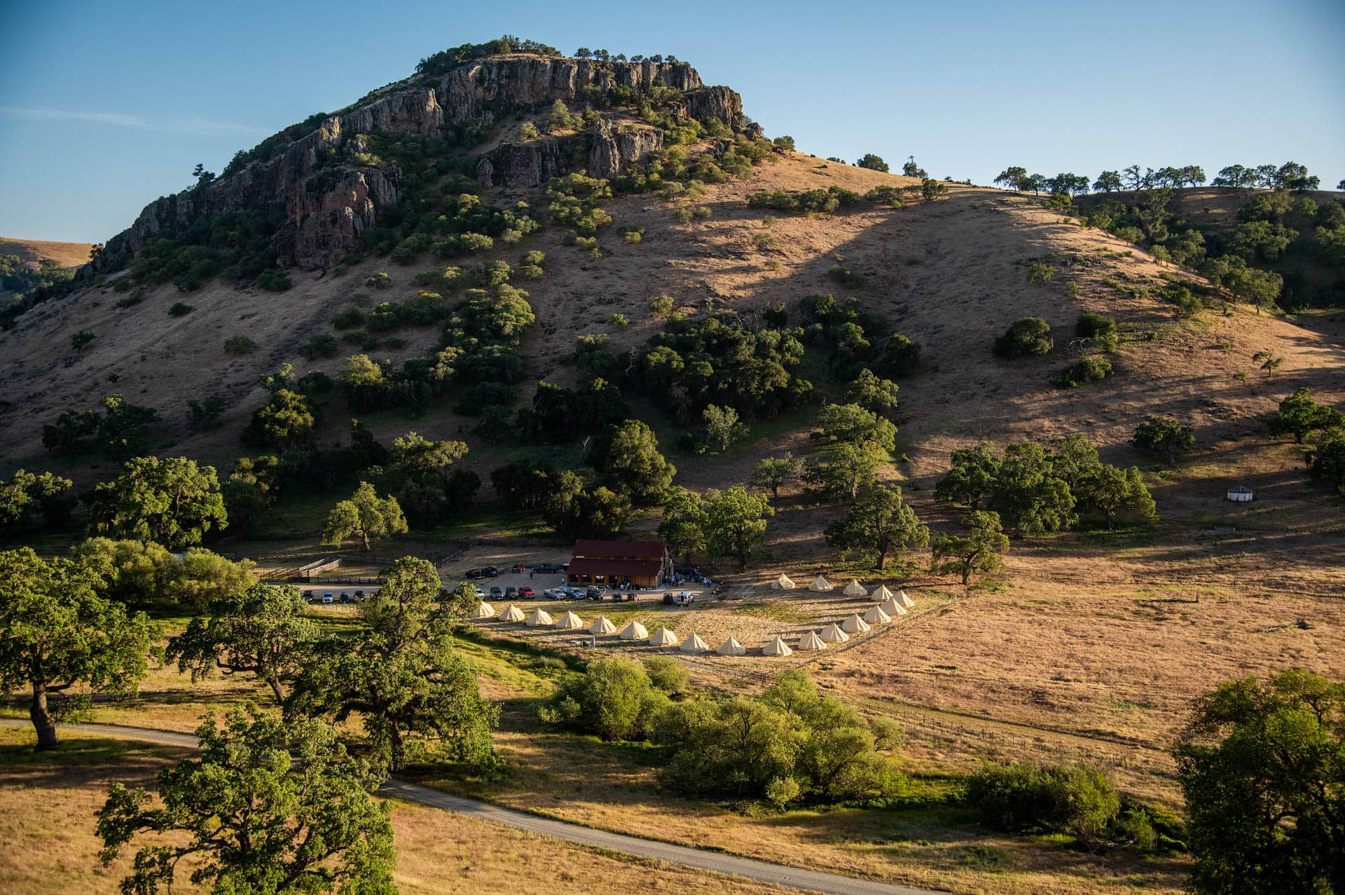 Scenic hill with trees and tent campsite below.