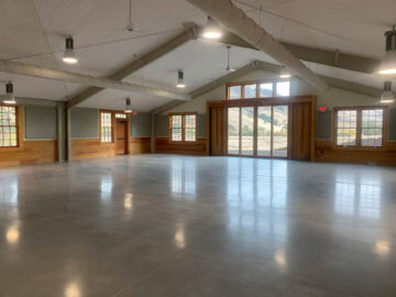 Spacious empty room with large windows and high ceiling.