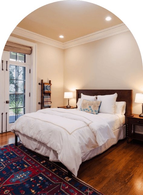 Cozy bedroom with a bed, lamps, and a colorful rug.