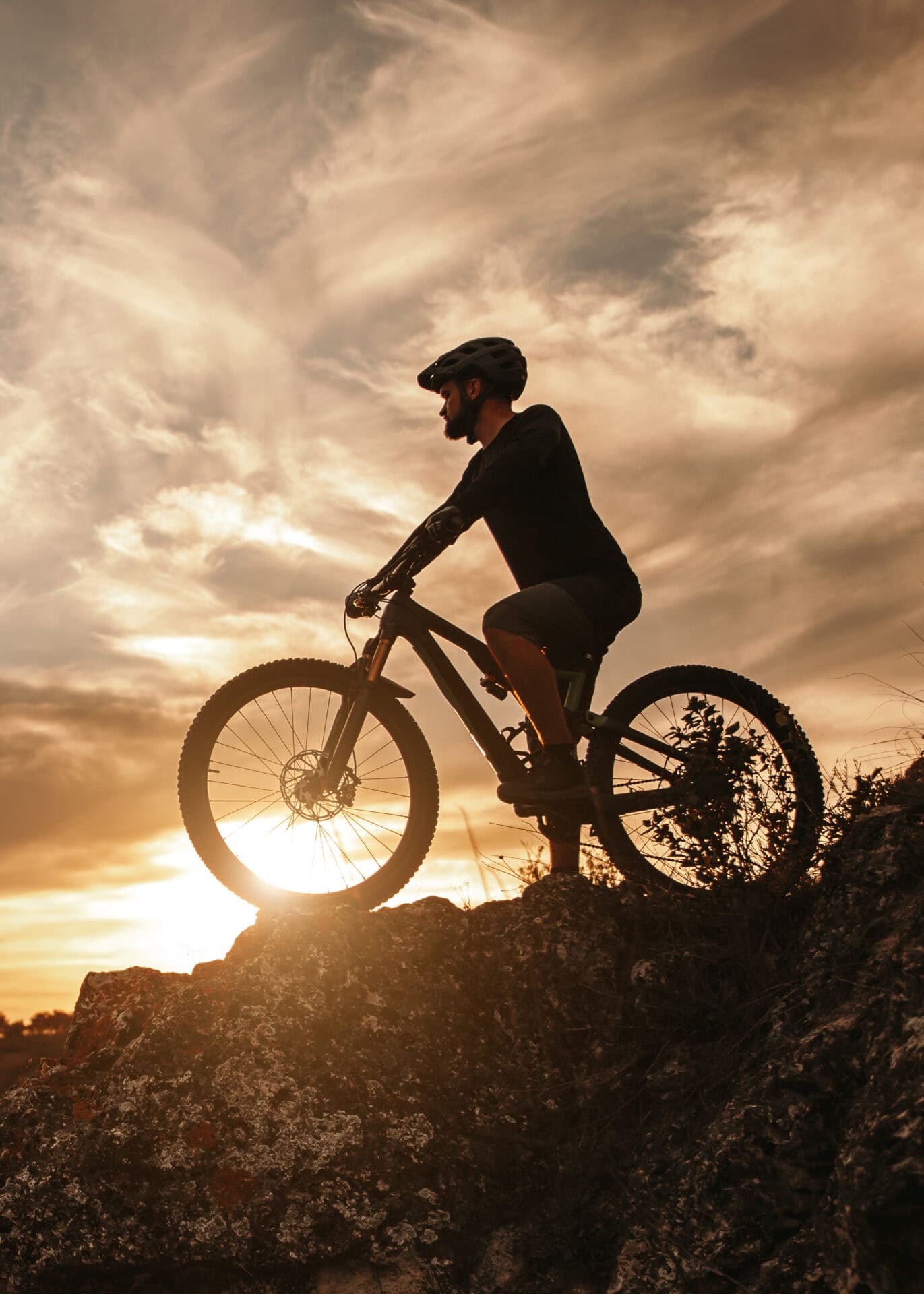 Silhouetted cyclist at sunset on rocky terrain