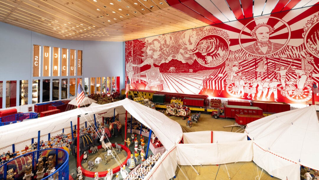 Indoor circus exhibit with mural and miniature tents.