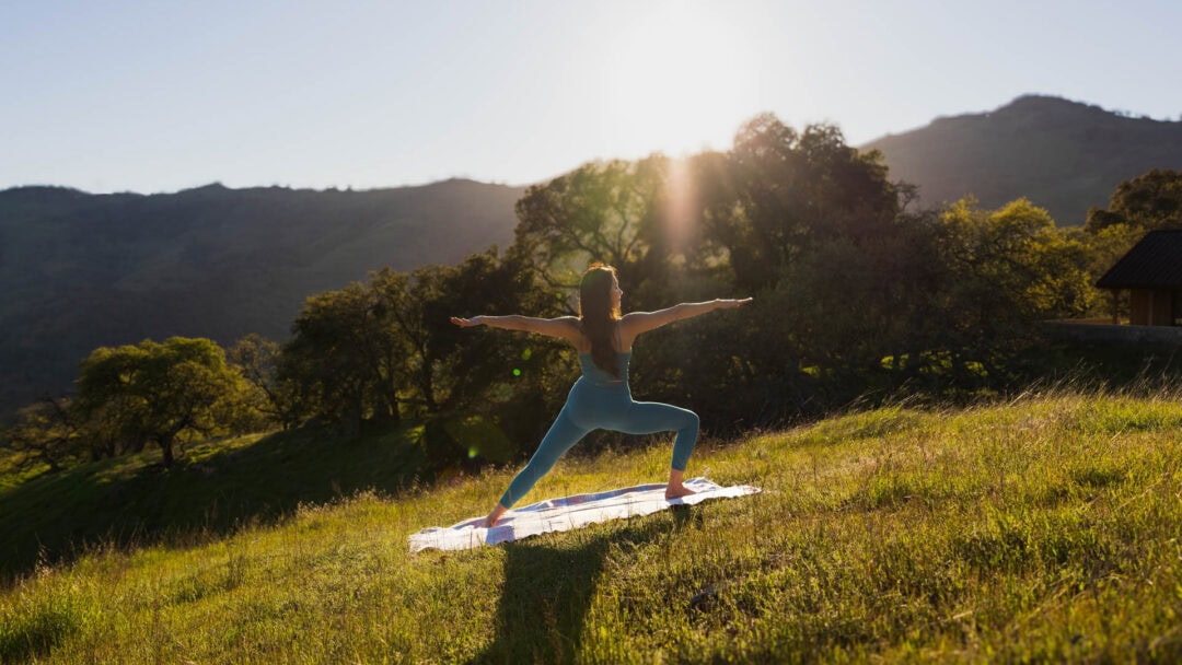 Woman doing yoga at sunrise in nature.