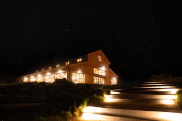 Lit barn at night under starry sky