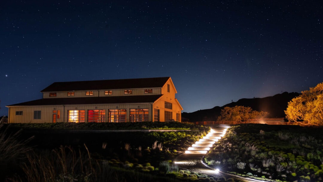 Illuminated farmhouse under starry night sky