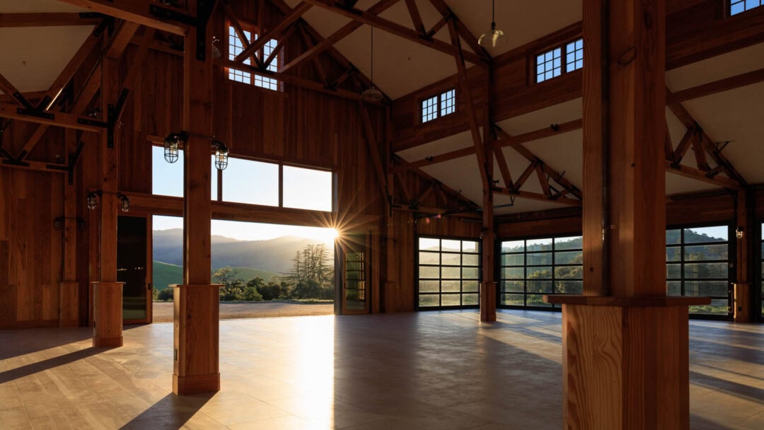 Spacious wooden barn interior with sunset view.