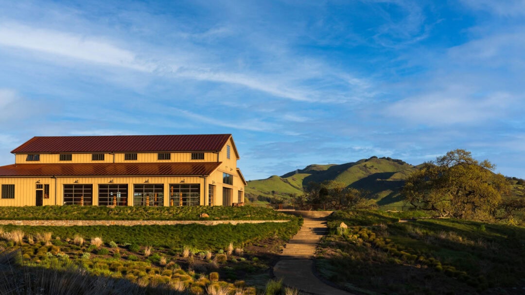 Yellow house near mountains and grassy field