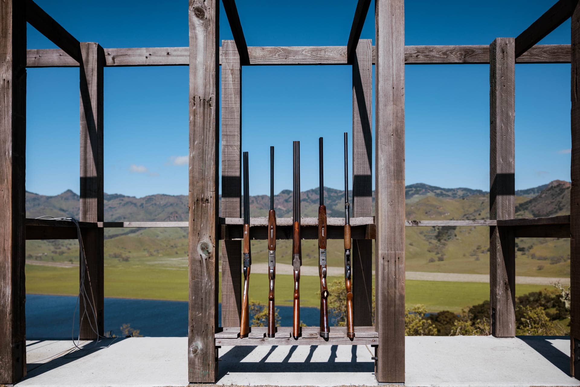 Rifles displayed on wooden frame with scenic background.