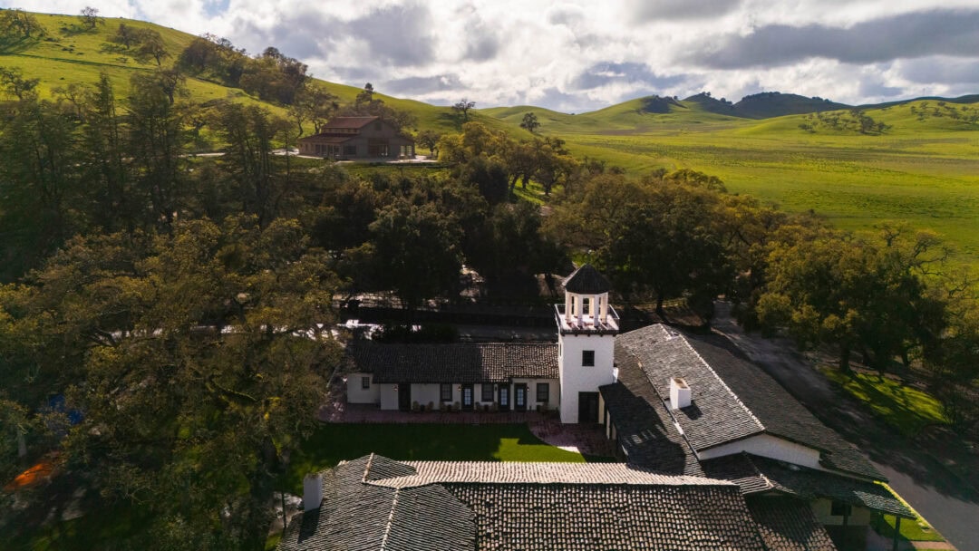 Aerial view of ranch house and green hills