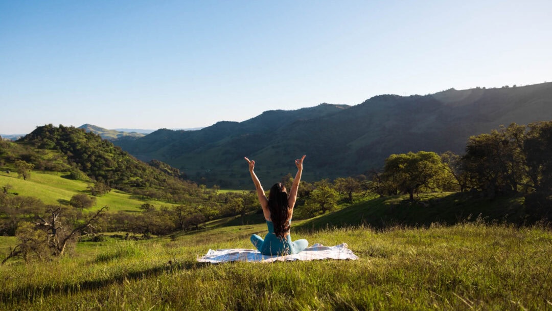 Woman meditating in scenic mountains