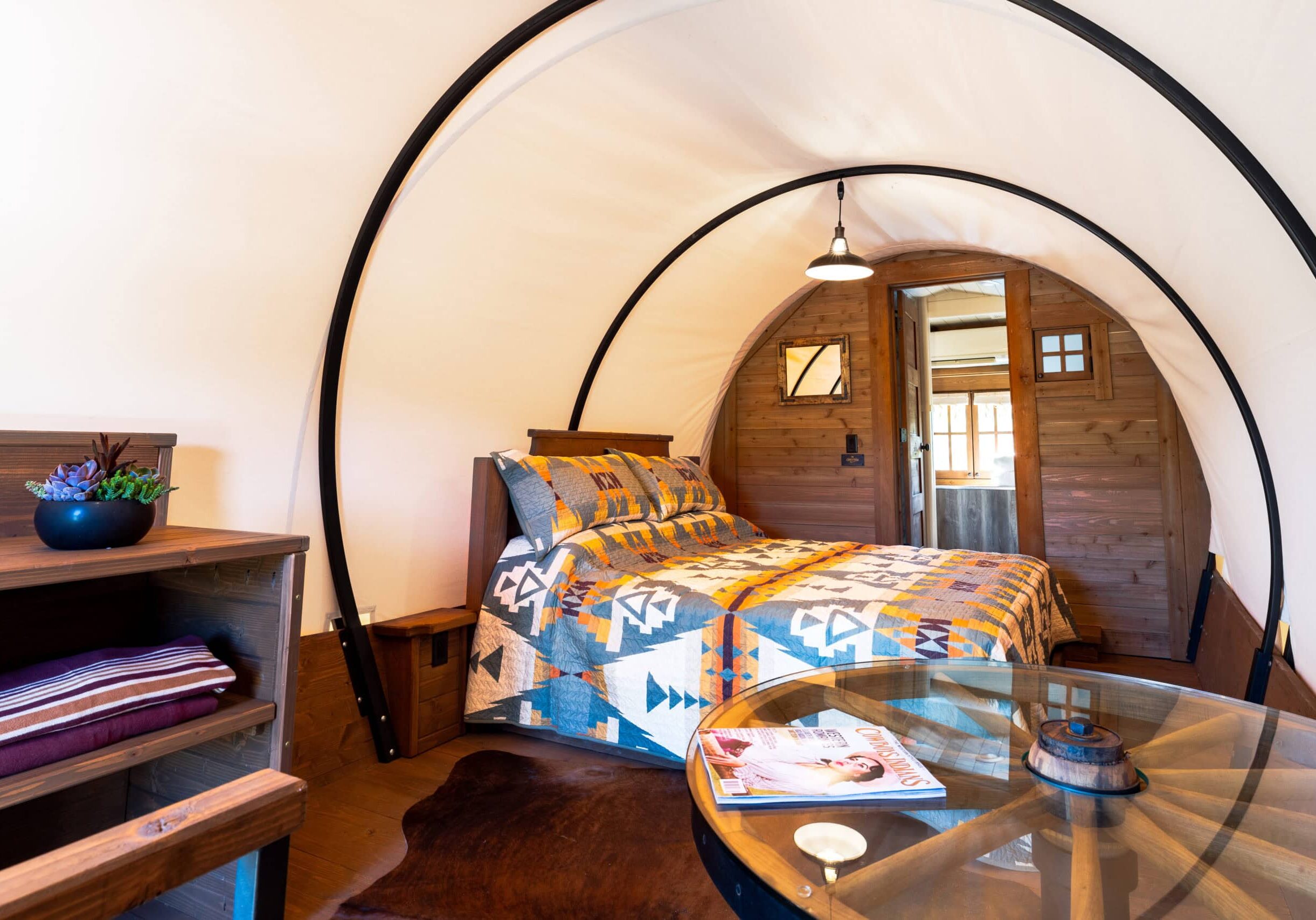 Cozy wooden cabin bedroom with colorful quilt and table.