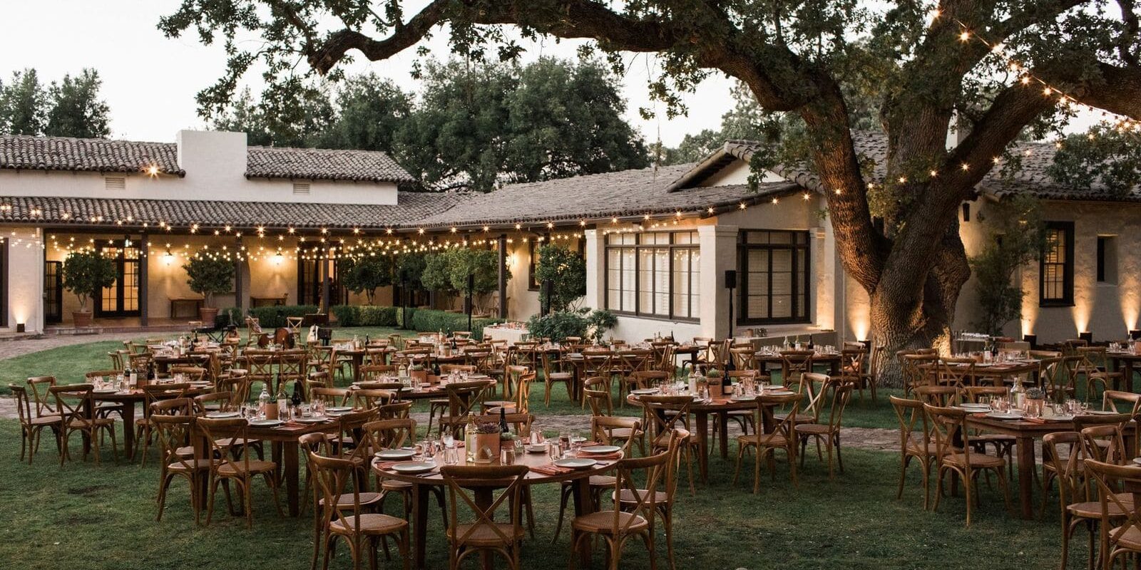 Outdoor wedding reception with string lights and decorated tables.